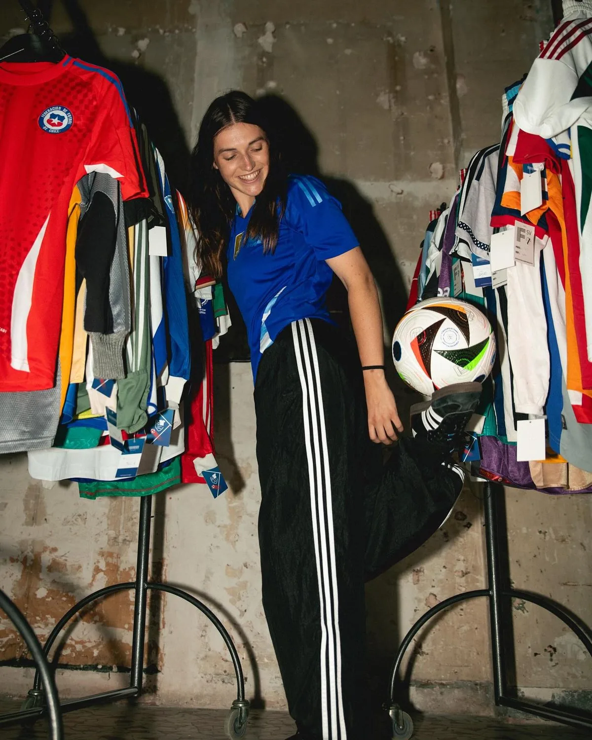 Yoanna Dallier adossée à un mur de maillots de football, ballon en main